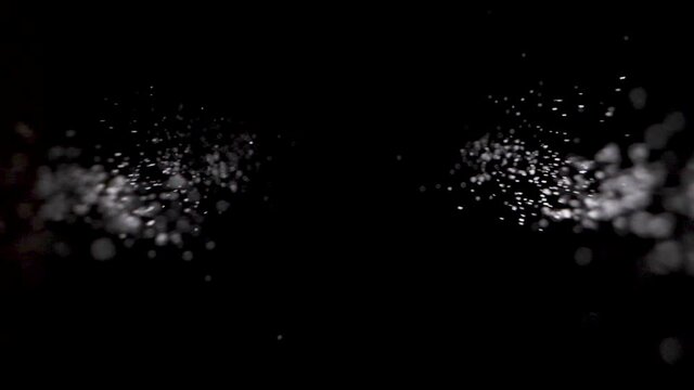 Sprinkle salt or glitter in slowmotion down into black background.