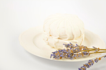Side view of Russian traditional soft dessert zefyr souffle served on plate with dried lavender flowers, isolated on white background. Dessert made of apple pectin, egg whites
