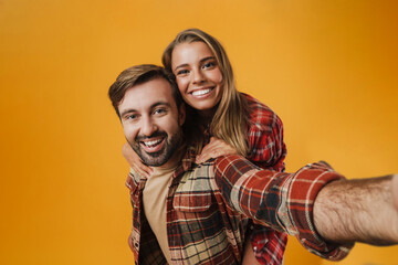 Excited man taking selfie while piggyback riding his girlfriend