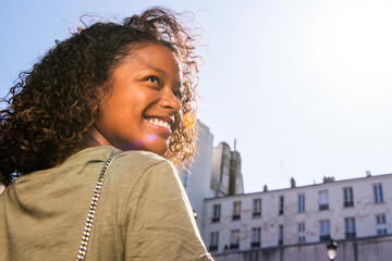 Close up young woman with curly hair looking over shoulder and smiling