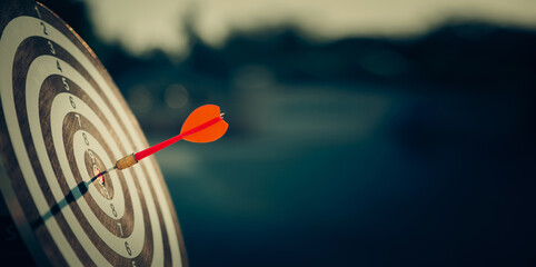 bullseye target or dart board has red dart arrow throw hitting the center of a shooting for...