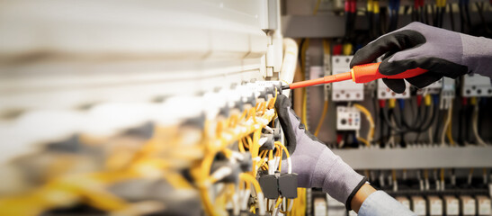 Electricians work to connect electric wires in the system, switchboard, electrical system in...