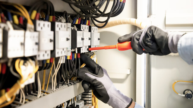 Electricians work to connect electric wires in the system, switchboard, electrical system in Control cabinet.