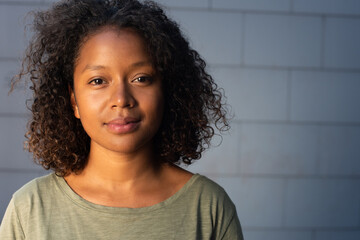 Close up attractive young African American woman with curly hair against gray background