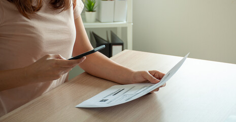 A woman uses a smartphone to scan the barcode to pay monthly phone bills after receiving an invoice...