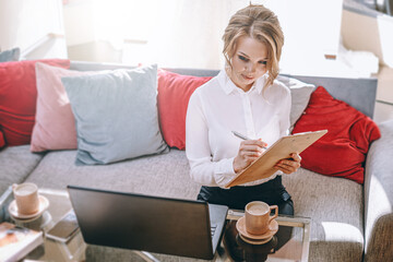 young woman wedding planner in office with laptop and tablet for writing