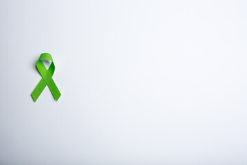 Green handmade awareness paper ribbon on white background.