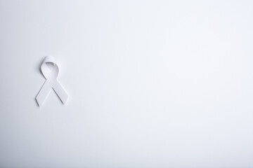 White handmade awareness paper ribbon on white background.