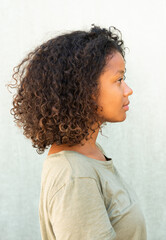 Side of young African American woman with curly hair against green background