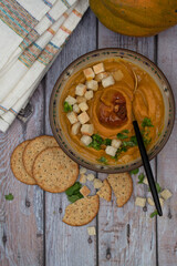 Vegan cream soup made with roasted pumpkin, carrot and tomato, topped with croutons, copy space