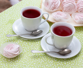 A couple of tea with red tea next to the marshmallows. Selective focus.