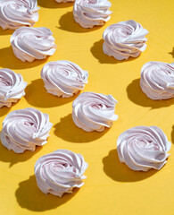 Pink marshmallow with a hard shadow on a yellow background. Selective focus.