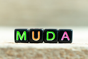 Black color block with word muda on wood background