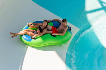 Girl and boy in water Park. Fun on the water. Teen girl and boy having fun in the water slider ....