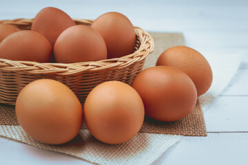 Eggs in the wicker basket on white wooden background for healthy food concept