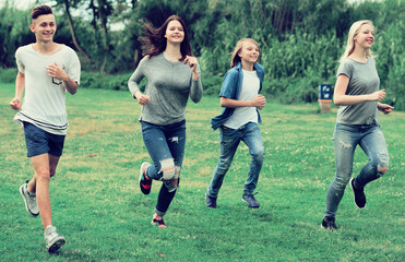 Fototapeta premium teenagers running through green lawn in summer in park