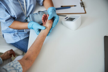 Medical person feeling the pulse of a senior citizen