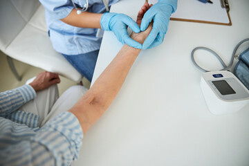 Medical worker pressing her fingers to a wrist vein