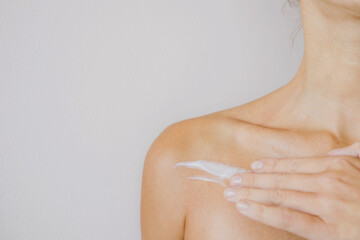 Woman putting on cream on her chest neck an shoulder
