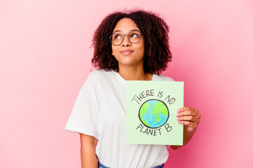 Young african american mixed race woman holding a world protection concept cardboard dreaming of achieving goals and purposes