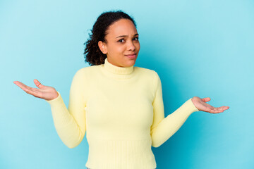 Young african american mixed race woman isolated doubting and shrugging shoulders in questioning...