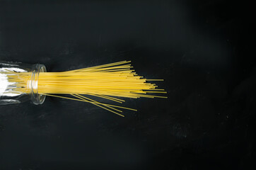 spaghetti pouring from the jar on a gray and black background