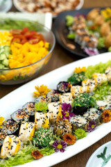 Colorful fruits salad and sushi rolls served on a white plate close up. Vegetarian food.