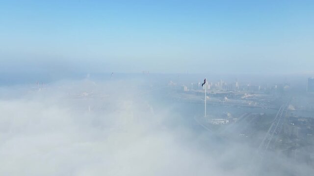 FOG IN UAE: Aerial view of Fog over Sharjah's Khalid Lake, Sharjah skyline  and flag island covered in the winter morning fog,  United Arab Emirates, 4K Drone Footage
