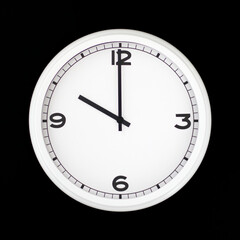 White round analog wall clock isolated on black background.