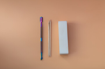 on a beige background, a pusher, orange sticks for manicure. The view from the top