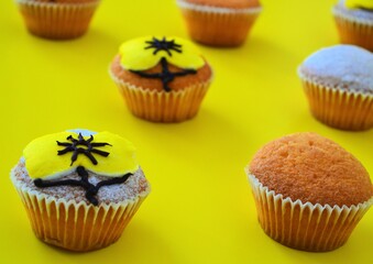 Rows of muffins decorated with powdered sugar and yellow flower shaped icing on a yellow background