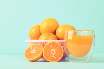 Fresh tangerine orange fruit and juice in glass on color background