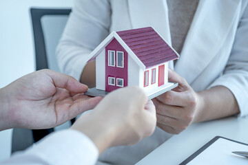 Home Model in hands, The real estate agent explains the business contract, rent, purchase, mortgage, a loan, or home insurance to the business buyer