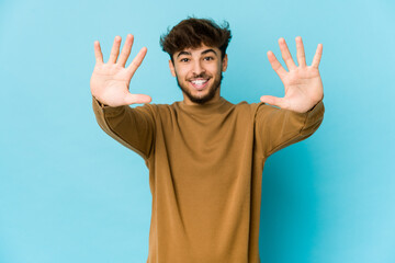 Naklejka premium Young arab man on blue background showing number ten with hands.