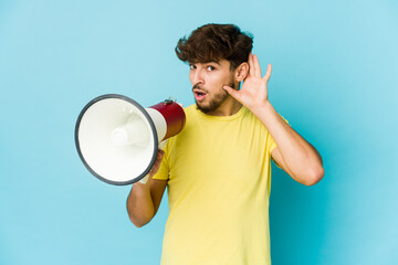 Young arab man holding a megaphone trying to listening a gossip.