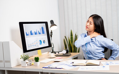 Asian female accountant is tired from working in a chair, stretching to relax and relax while working hard at the office