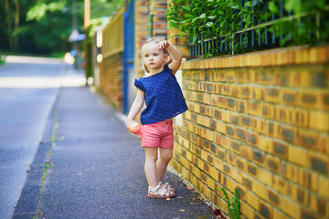 Adorable toddler girl standing against brick wall