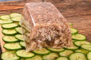 Meat jelly or brawn on a plate. Homemade head cheese on cucumber slices