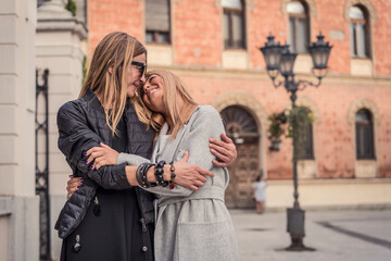 Beautiful and fashionable mature mother and young daughter outdoors in city with fresh new clothes. Fashion for mothers and daughters. Happy mother and daughter love. Family love.