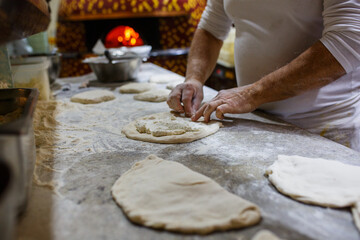 Pizzaiolo mentre chiude una pizza ripiena di ricotta e salame napoletano