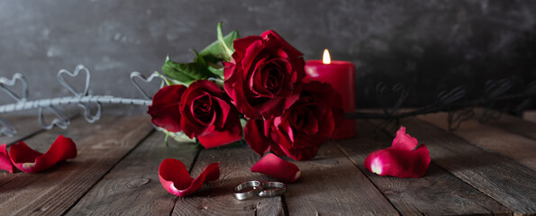 Romantic love decoration with wedding rings red roses and candlelight in vintage style. Horizontal...
