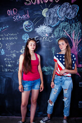 back to school after summer vacations, two teen real girls in classroom with blackboard painted together, lifestyle people concept