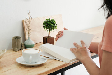 Obraz premium Mockup image of a woman reading a book on table with blank pages of book