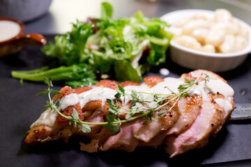 Smoked duck breast in sauce served with a green salad. soft focus image.