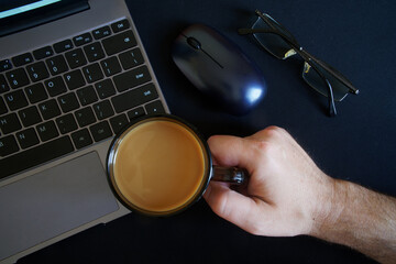 A man holds a mug of coffee with milk while sitting at a modern laptop or ultrabook. Risk of damage and loss of warranty.