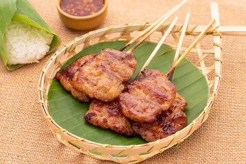 Grilled pork skewers or moo ping in Thai served on bamboo basket