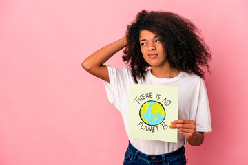 Young african american curly woman holding a planet message on a placard touching back of head, thinking and making a choice.