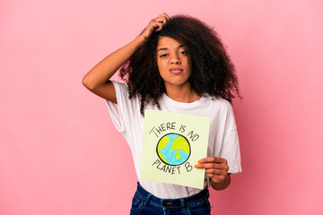 Young african american curly woman holding a planet message on a placard being shocked, she has...
