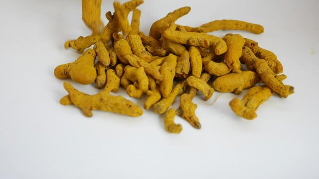 View of dropping turmeric over a white background, Turmeric being dropped over white background