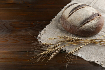homemade bread and ears of wheat on a wooden background